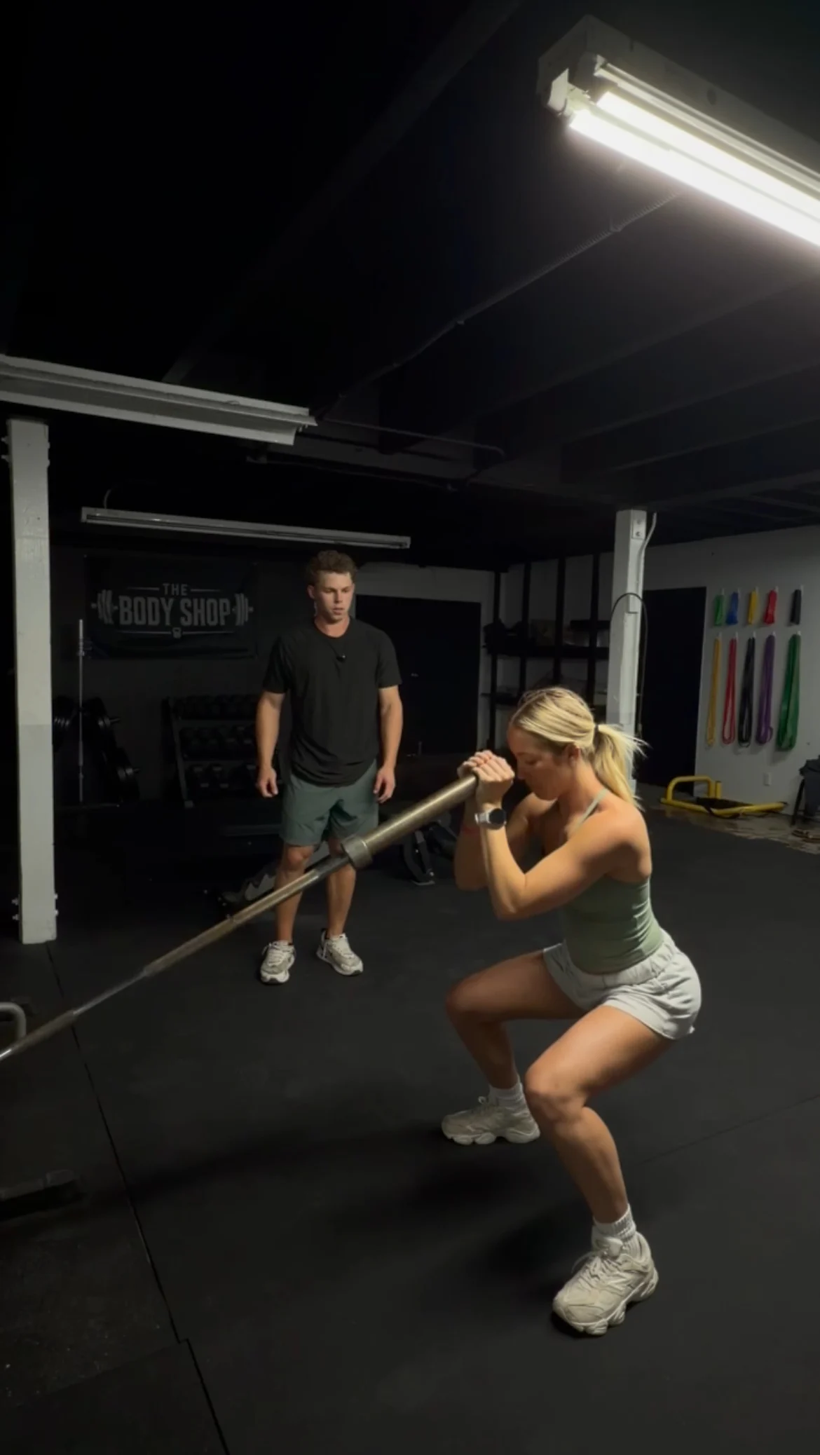 A female athlete performing a landmine exercise while Jarrod Hocking coaches