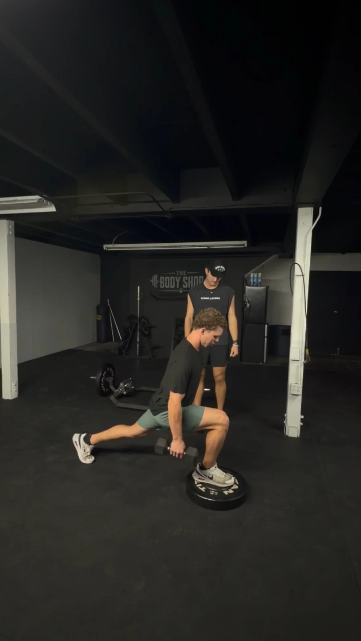 An athlete performing a split squat while Jarrod watches